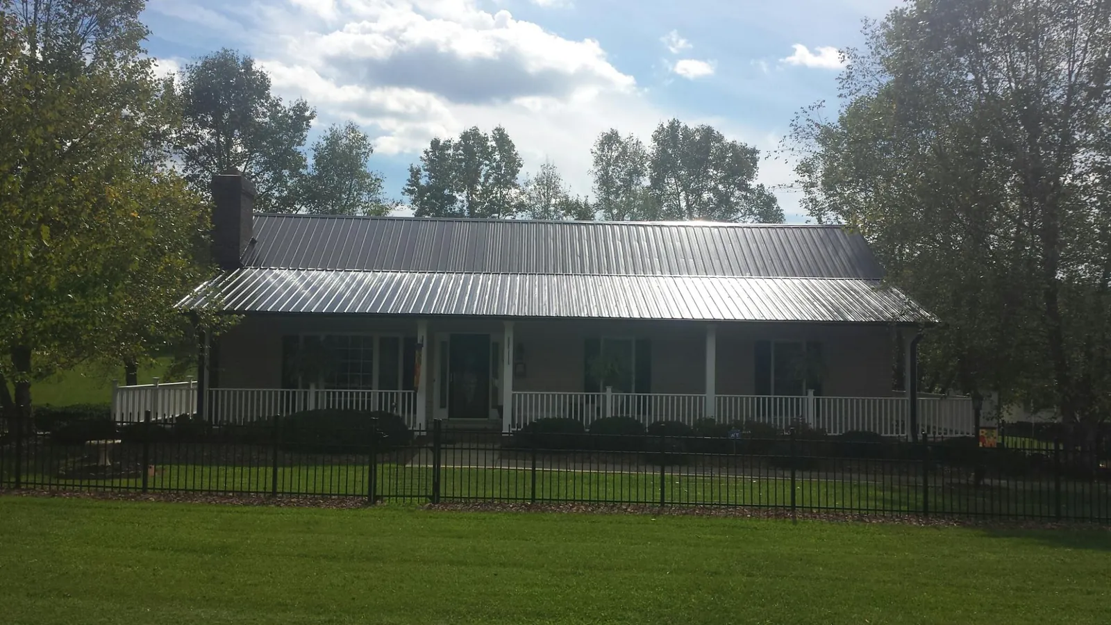 Gray metal roof on a brick ranch with a full width front porch — Gutter Guard Installation work by our crew in Jacksonville